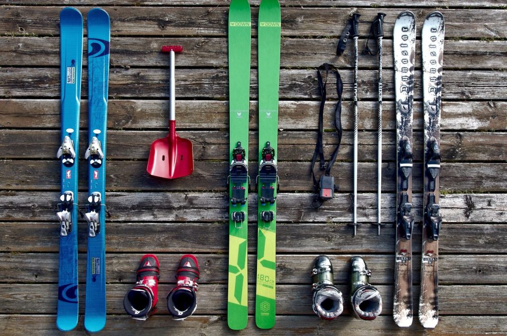 Collection of ski gear on a wooden deck, showcasing vibrant colors and vintage style.