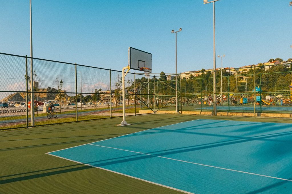 An empty outdoor basketball court with a scenic background under a clear blue sky during the daytime.