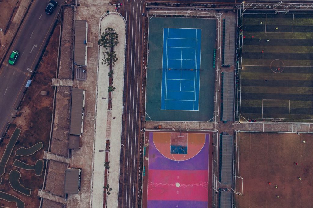 Top-down aerial shot showcasing tennis, soccer, and colorful basketball courts.