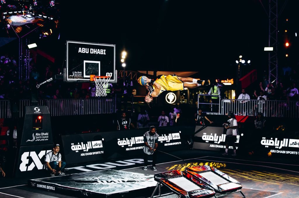 Athlete performs a dynamic slam dunk during a basketball tournament in Abu Dhabi.