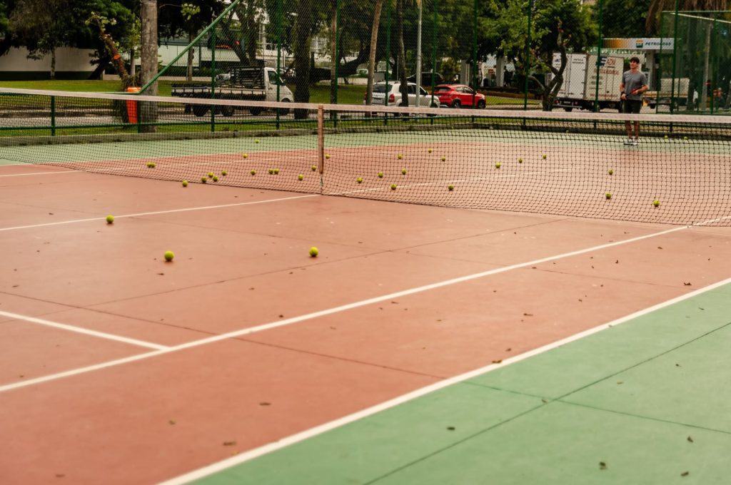 Tennis court with scattered tennis balls across the surface, ready for play.