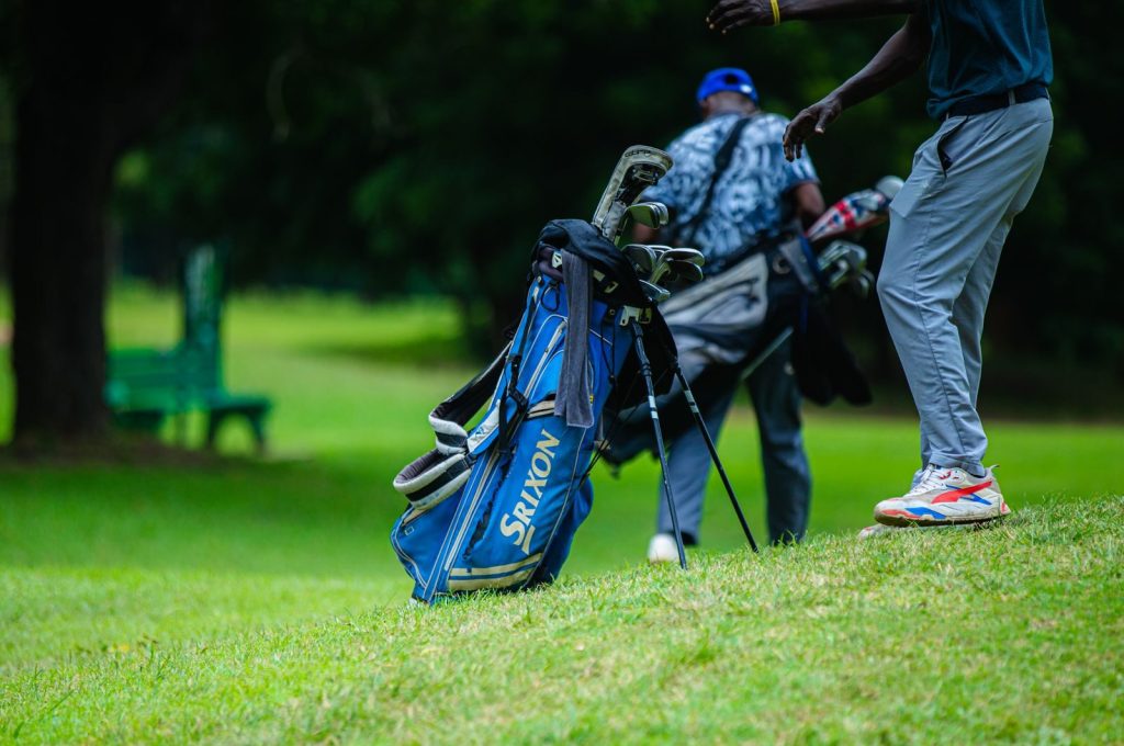 Golfers walking with clubs on a lush green golf course, perfect day for a round.