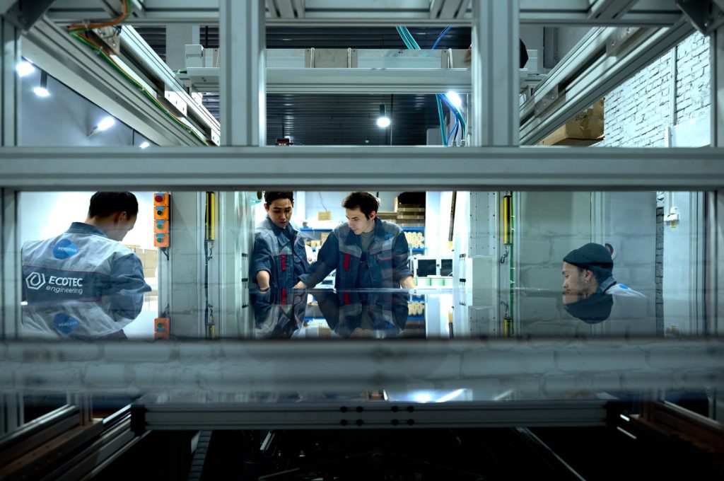 Engineers collaborate over advanced machinery in a high-tech indoor workspace.