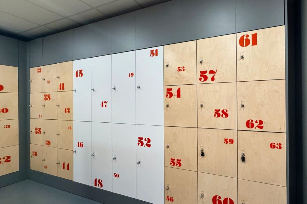 A row of modern wooden lockers with red numbers in a Finnish building.