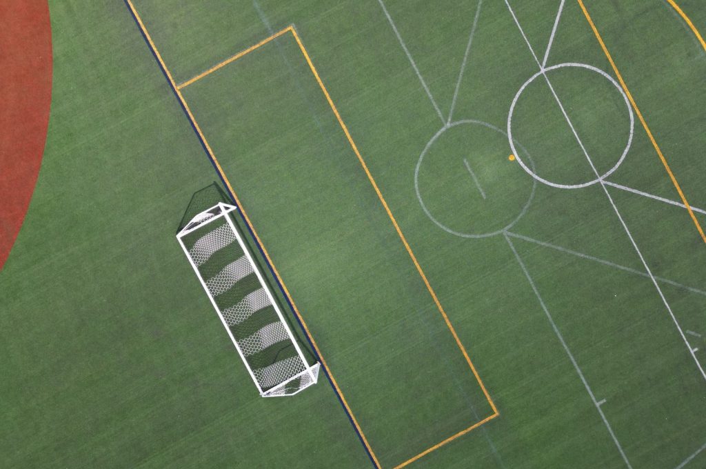 Top-down view of a vibrant, empty soccer field highlighting the goal net and pitch lines.