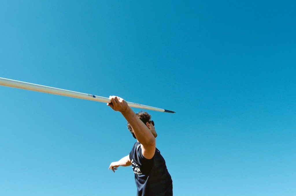 A young athlete prepares to throw a javelin outdoors on a sunny day, capturing the essence of competitive sports.