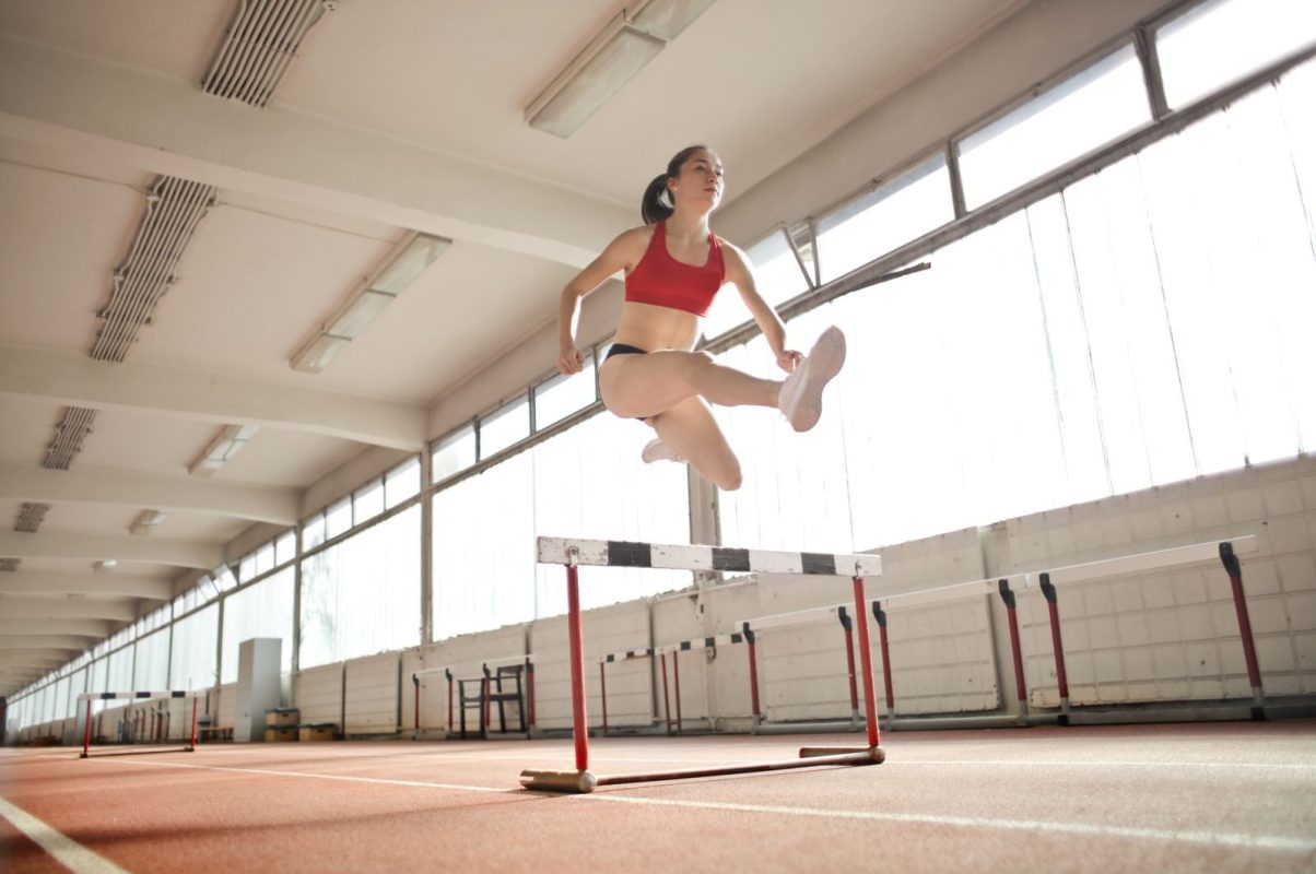 Dynamic action shot of a woman hurdling indoors, showcasing strength and agility.