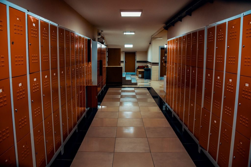 Vacant locker room with orange lockers and tiled flooring in a modern sports facility.