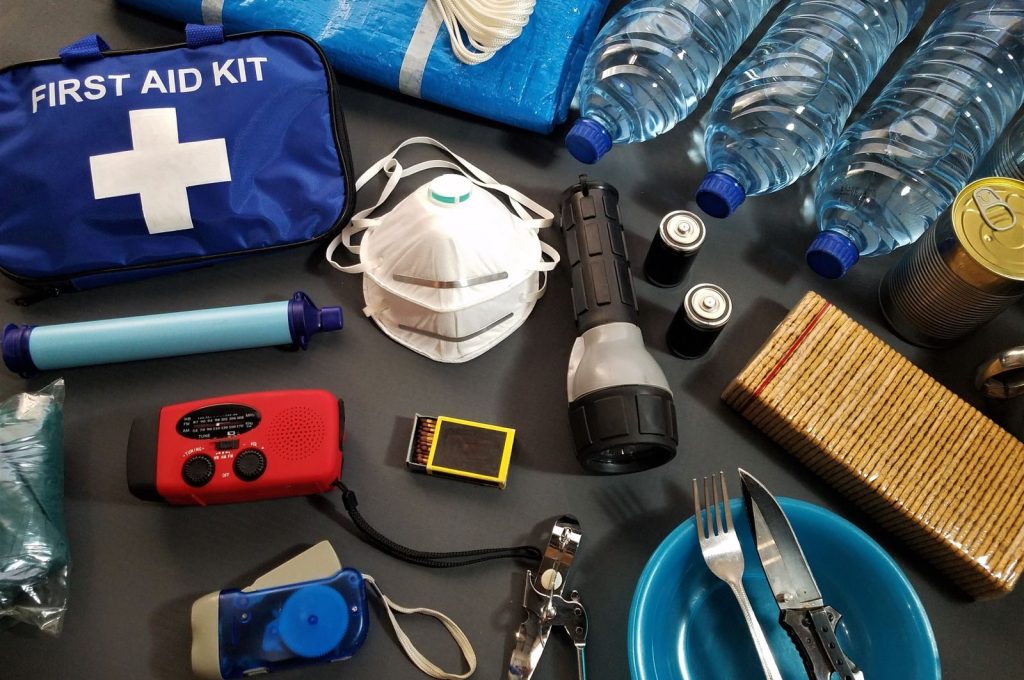 Flat lay of essential emergency survival kit items including first aid and water bottles.
