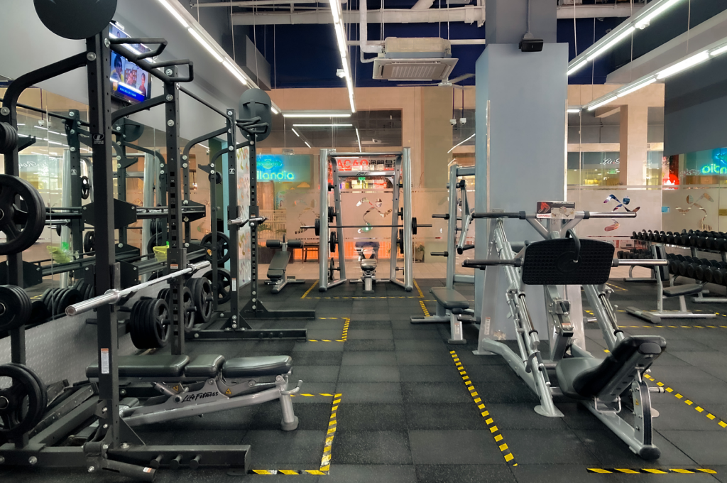 A spacious gym featuring modern exercise equipment and weights, ideal for fitness routines.