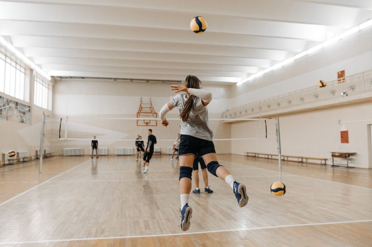 A dynamic volleyball match taking place in an indoor sports hall with players engaging actively.