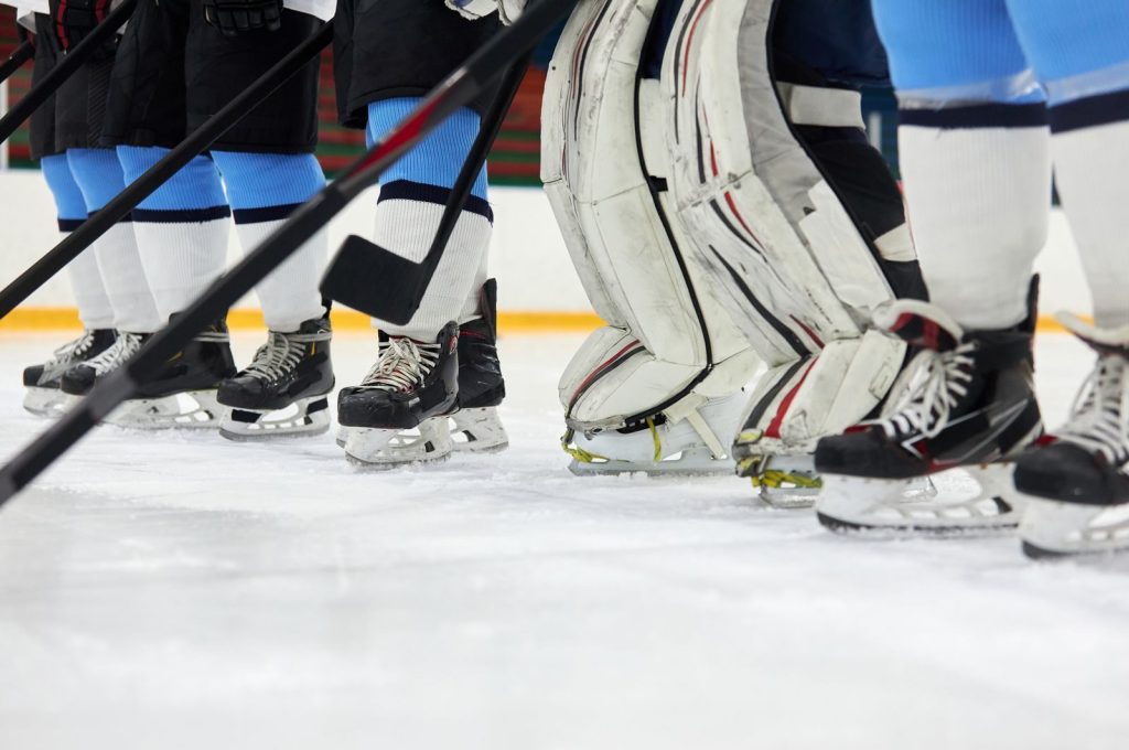 Focused view of hockey players' skates and sticks on an ice rink, ready for action.