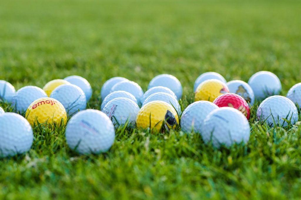 A close-up of colorful golf balls on green grass, ideal for sports and recreation themes.