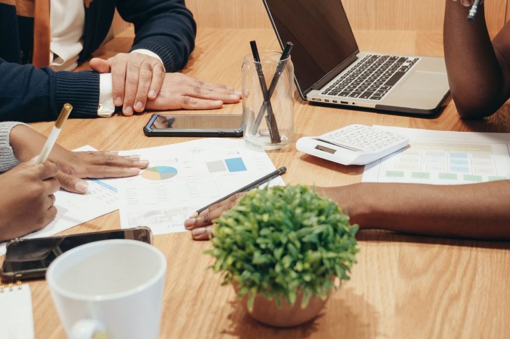 Diverse team collaborates on a business project with charts and laptops in a modern office setting.