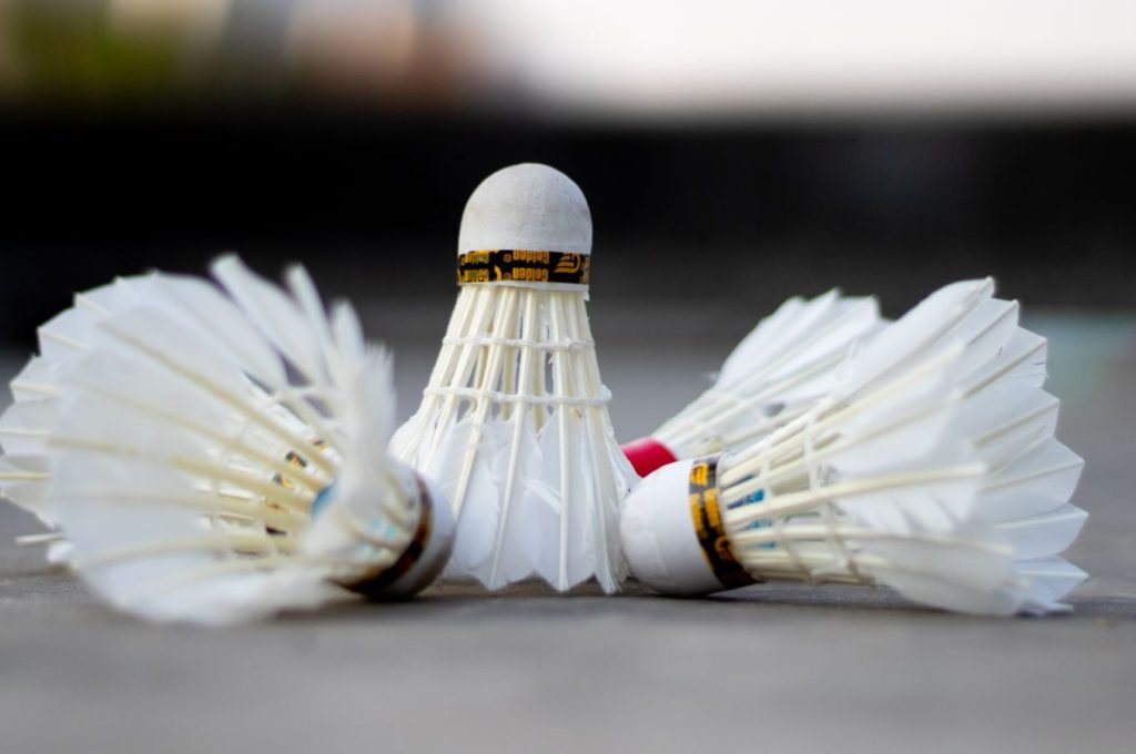 Detailed view of three badminton shuttlecocks laying on a court surface.