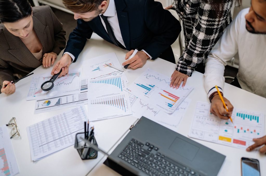 A group of professionals reviewing financial charts in an office meeting setting.