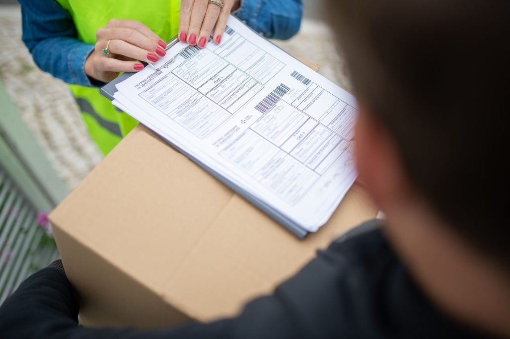 Courier hands over a package for delivery with signing of receipt documents.