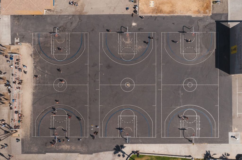 Drone shot of urban basketball courts, vibrant sports scene from above.