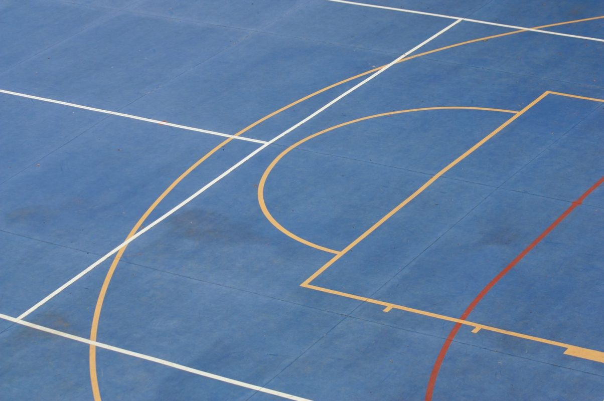 Close-up of a basketball court with colorful lines on a blue background.