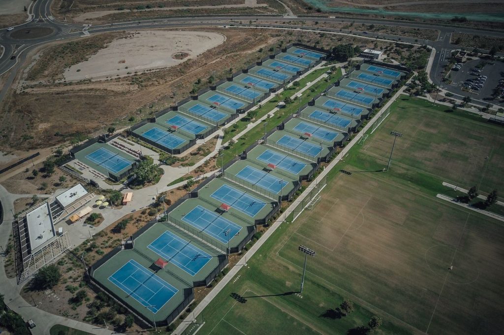 High-angle view of multiple tennis courts in a landscaped area, suitable for sports activities.